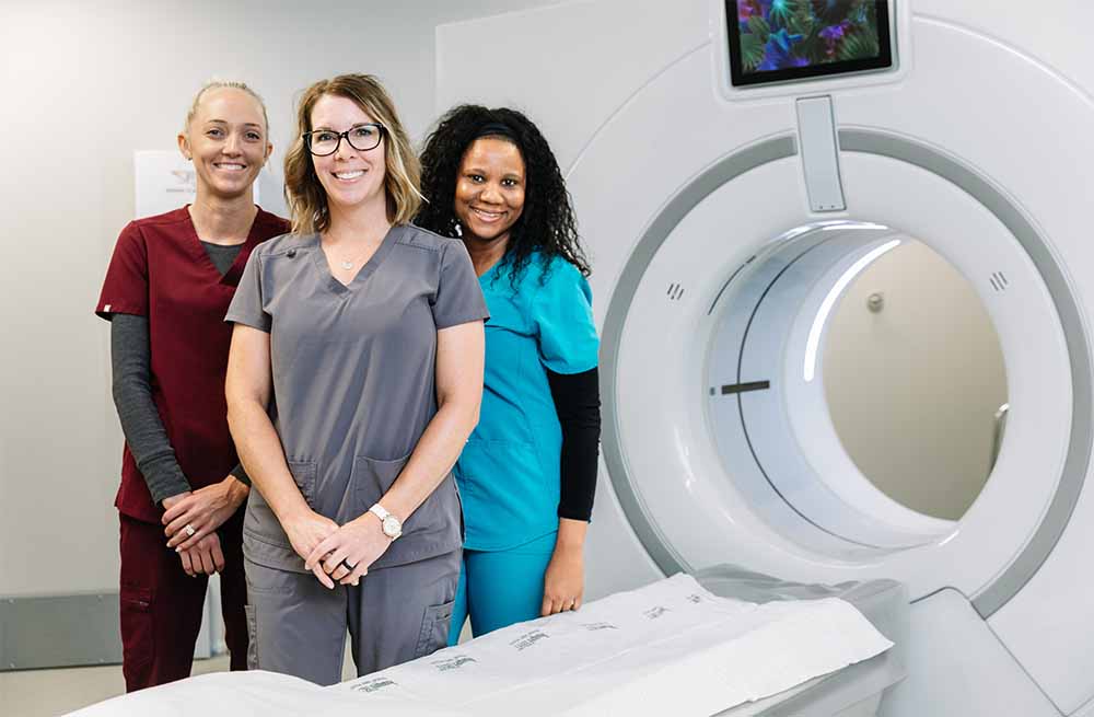 Three nurse practitioners in a Springfield clinic imaging room standing next to MRI machine.