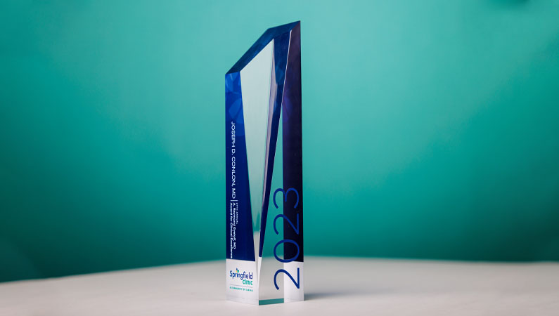 2023 Eveloff Award in front of a blue backdrop.