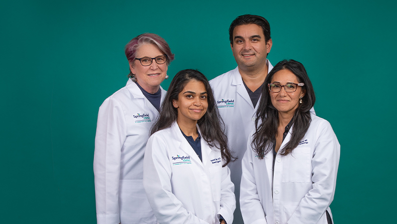 Group of medical professionals smiling front of a green background