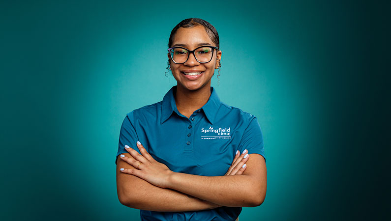 Young female wearing green shirt smiling in front of green background