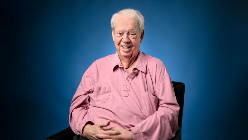 Patient smiling in front of navy blue backdrop.