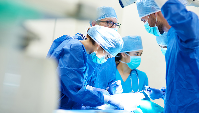 Group of surgeons in protective medical gear in operating room
