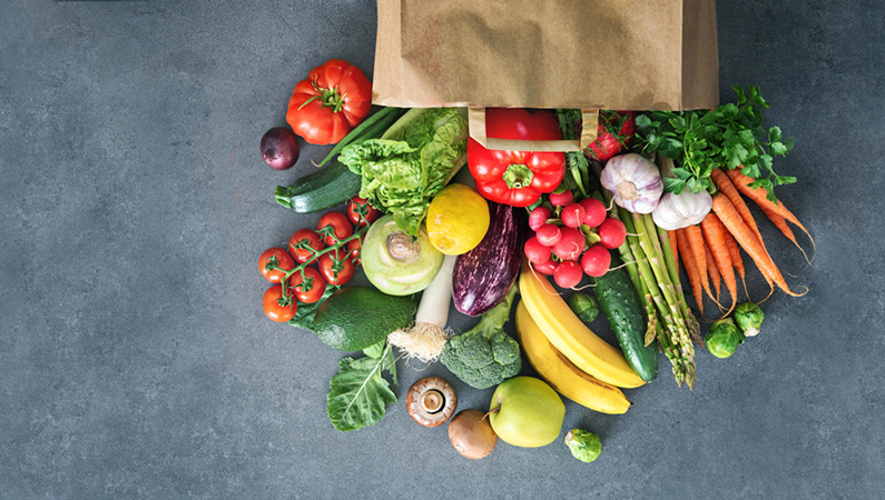 Brown paper bag with fresh fruit and veggies pouring out
