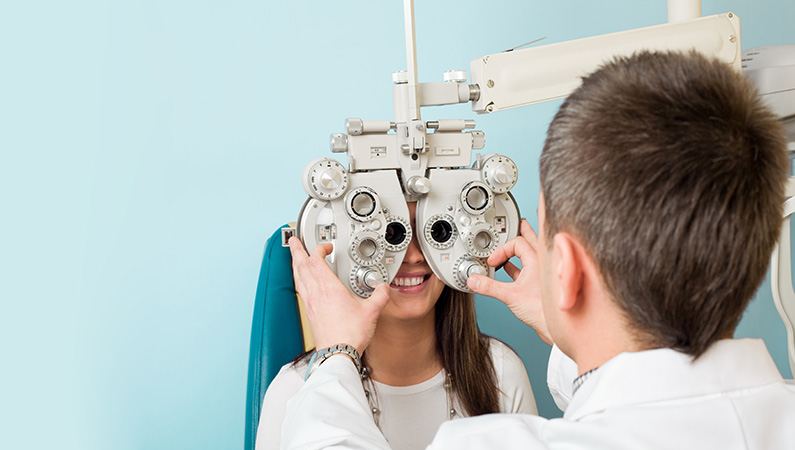 Patient in light blue exam room getting eyes checked by medical professional