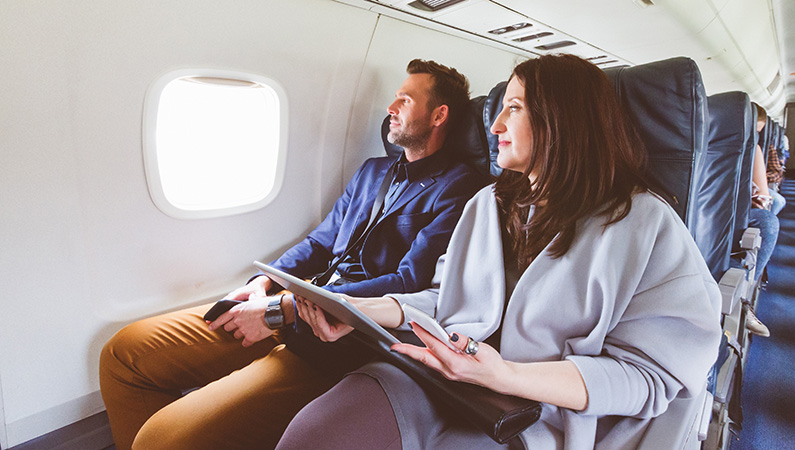 Two individuals on airplane looking out window