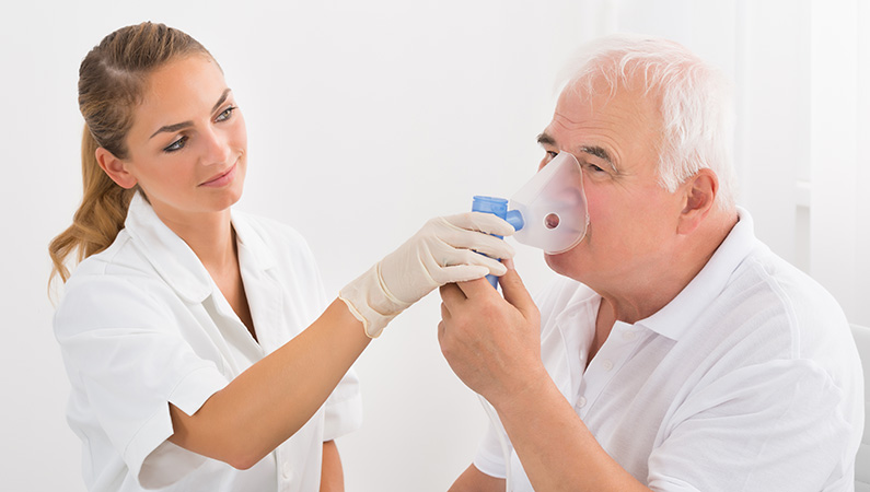 Elderly male patient getting breathing treatment from medical professional