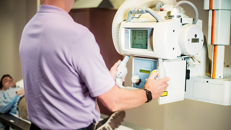 Radiologist performing x-ray on young male patient