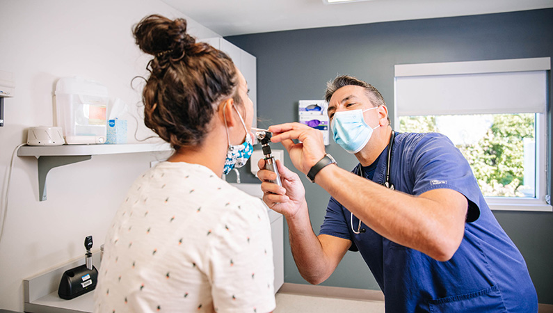 Female patient in clean exam room getting throat checked by doctor