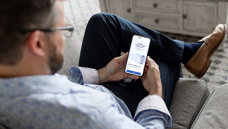 Male in business attire looking at a mobile phone.