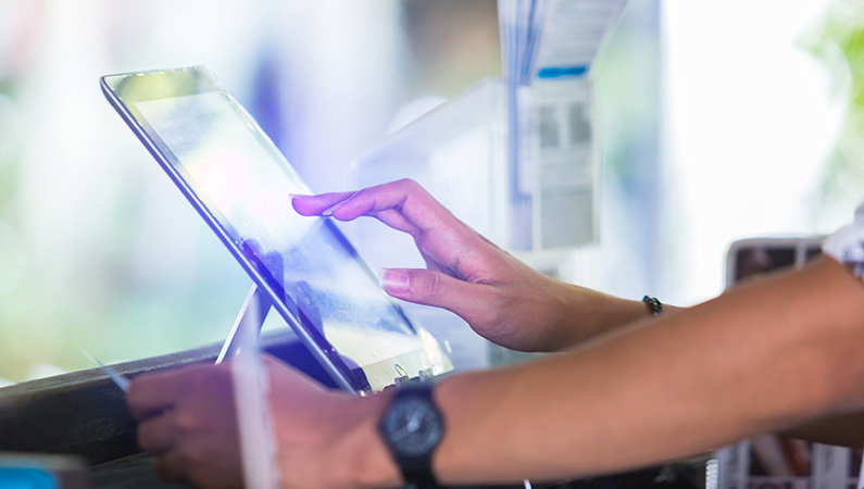 Closeup of someone using a tablet with a credit card in one hand