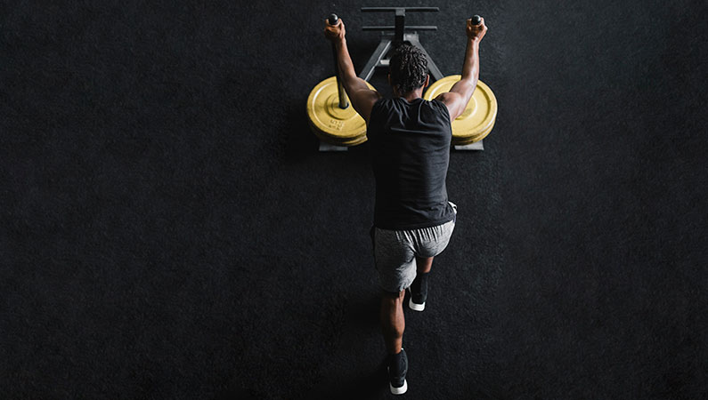 Male in workout clothing pushing weights