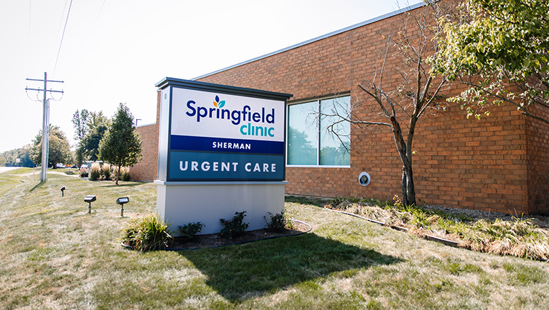 Exterior sign in front of single story brick medical urgent care facility in Sherman, Illinois