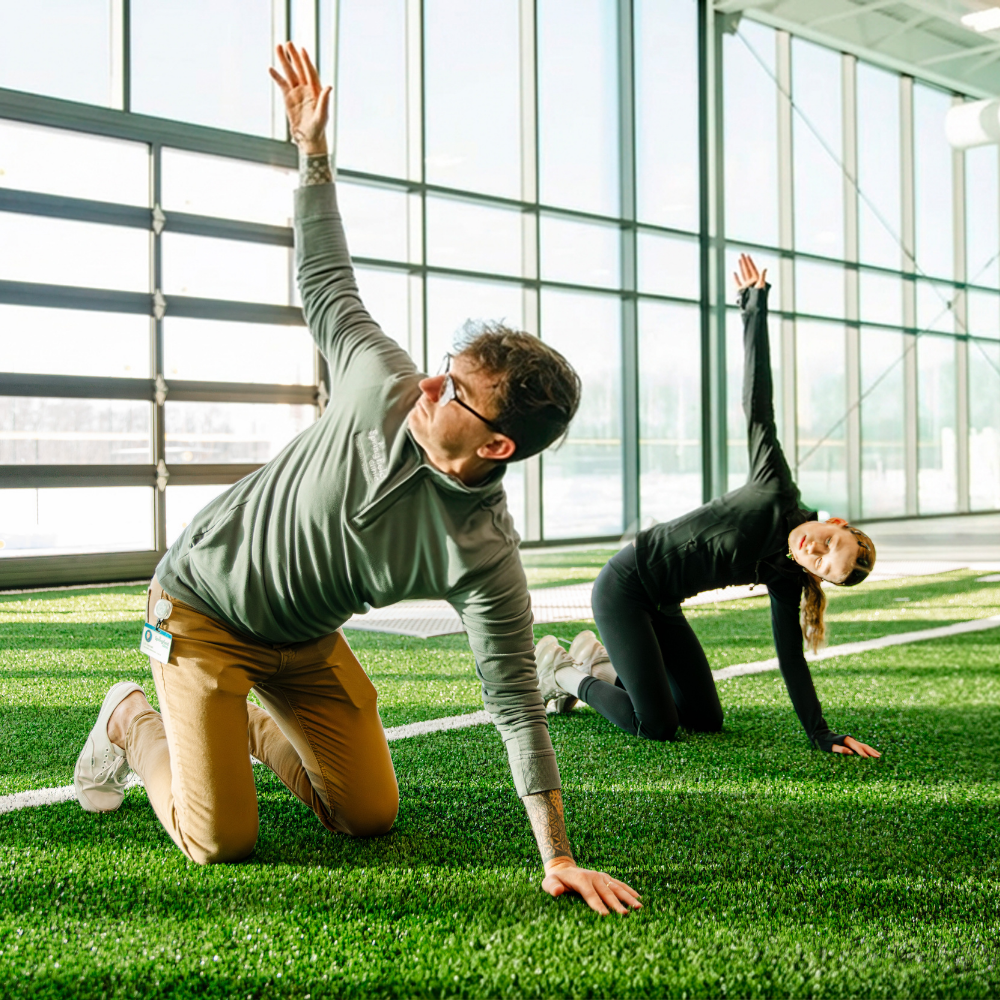 Male personal trainer with youth athlete in well-lit fitness center