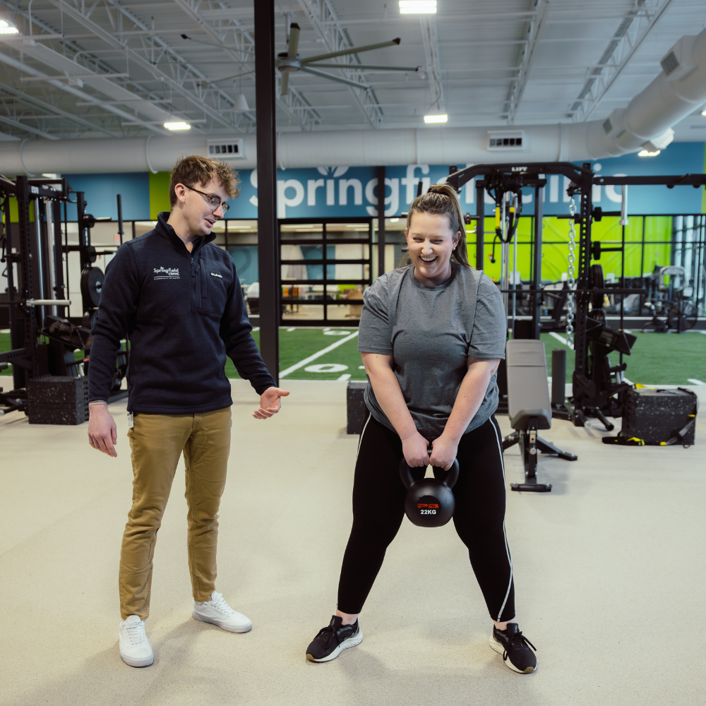 Male personal trainer with female athlete in a fitness center