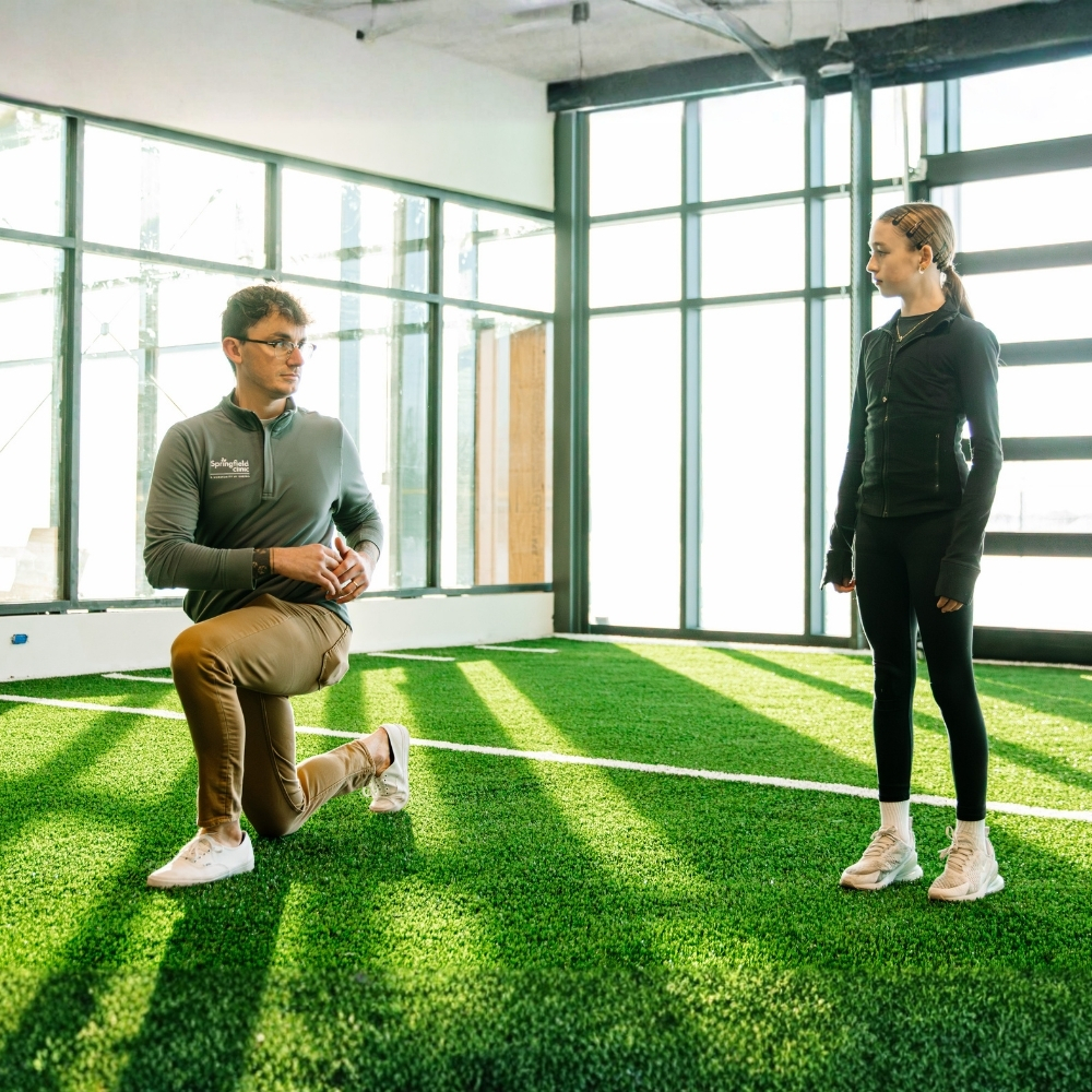 Male personal trainer with youth athlete in well-lit fitness center