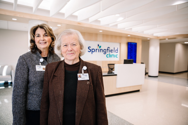 Two female greeters smiling in well-lit lobby