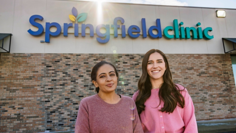 Two primary care providers smiling posing together outside of their Springfield Clinic location in Peoria, Illinois.