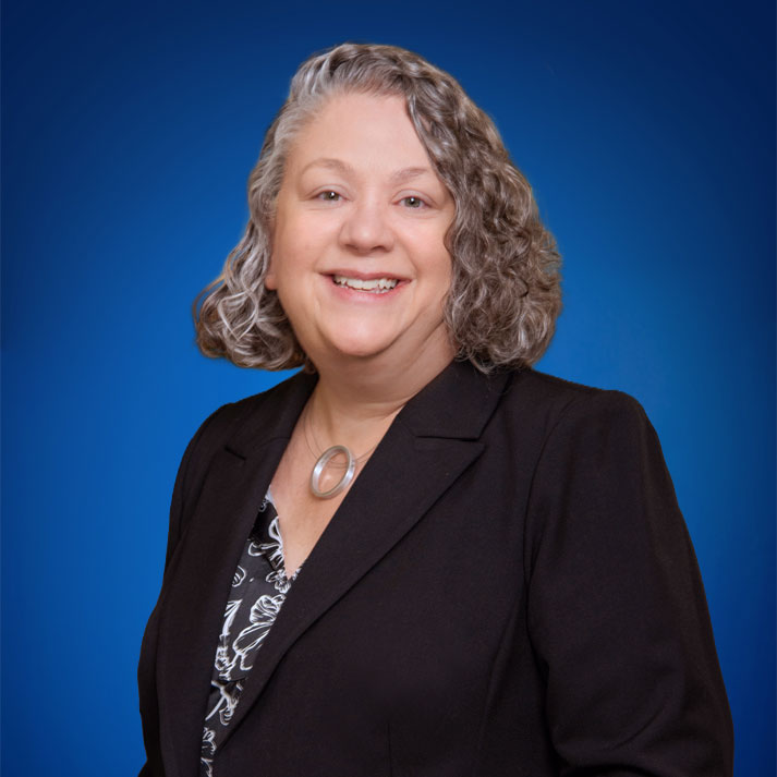 Rebecca Birenbaum smiling in front of blue background