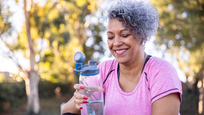 Female with bottle of water in outdoor setting.