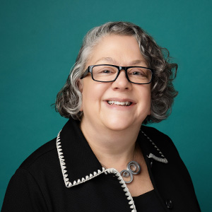 Professional headshot of business professional smiling in front of green background
