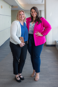Two women standing arm in arm and smiling