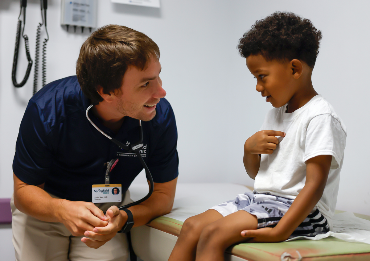 A male doctor talking to a male pediatric patient
