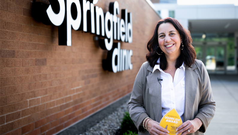 Mindy Vance, APRN, CNP, smiling holding Springfield Clinic 2024 Golden Leaf Award.