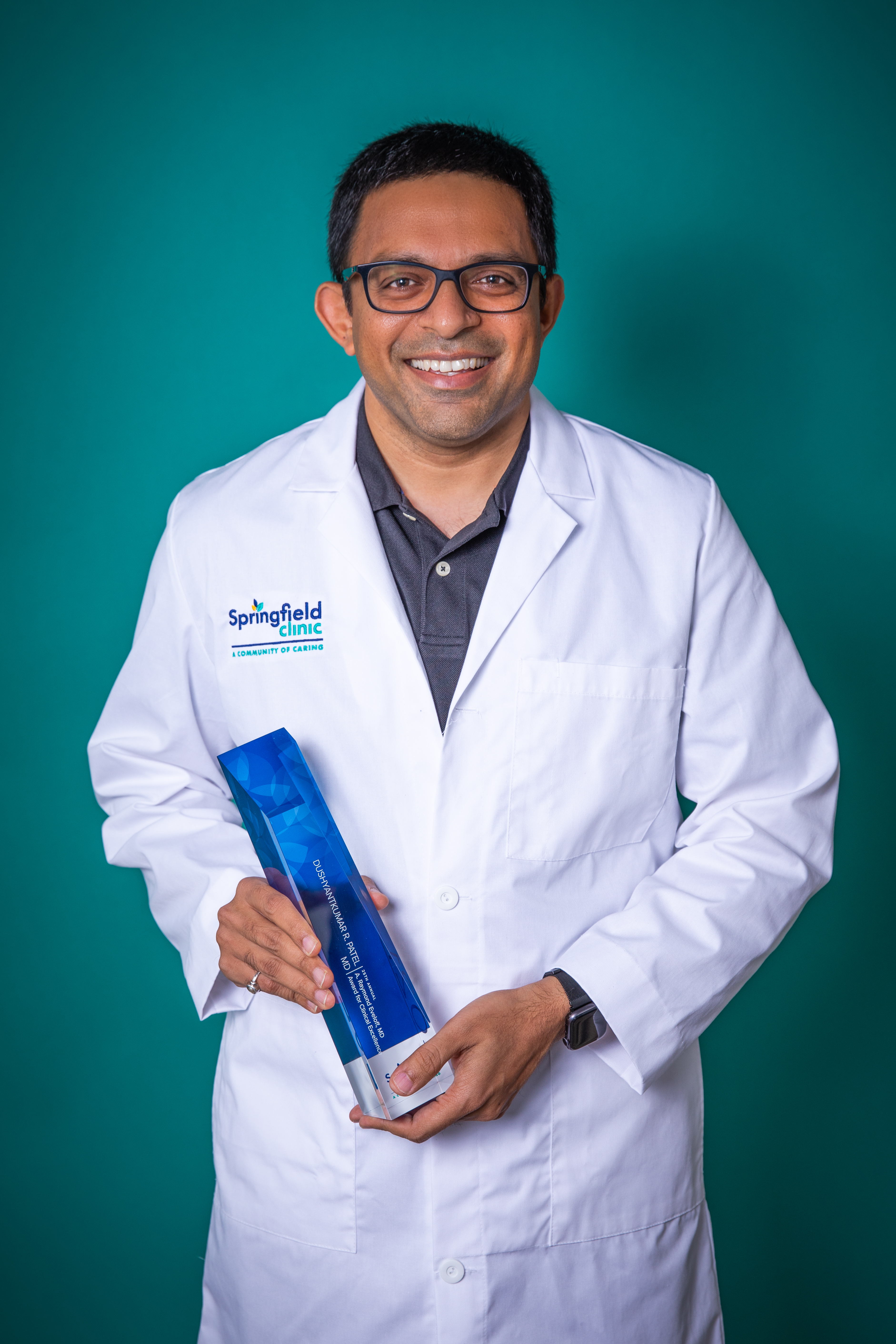 Dushyantkumar R. Patel, MD, holding the 2021 Eveloff award in front of a green background.
