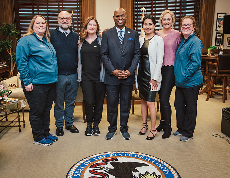 Dr. Dayoub smiling with four nurses, Illinois State Rep. Barbara Hernandez and Illinois Speaker of the House Emanuel “Chris” Welch in his office.