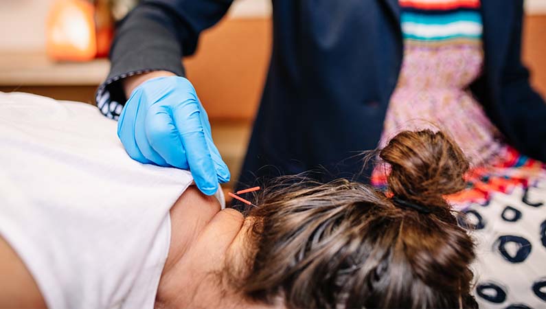 Chiropractor applying acupuncture on a patient's neck.