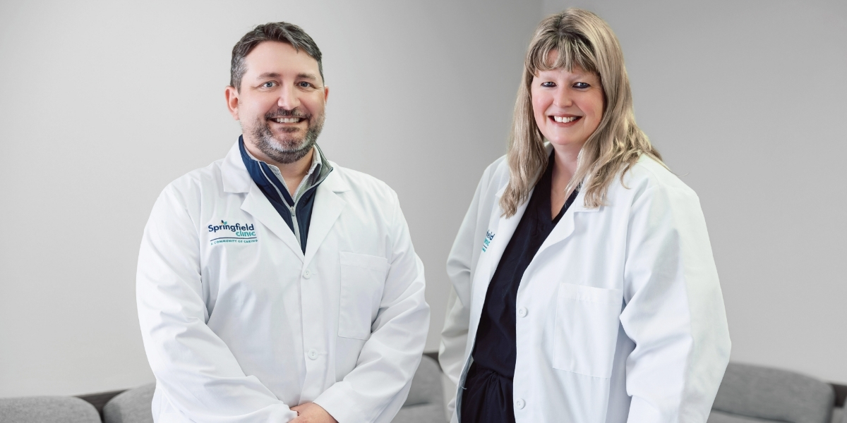 Two board-certified podiatrists posing in white medical coats in patient waiting room area