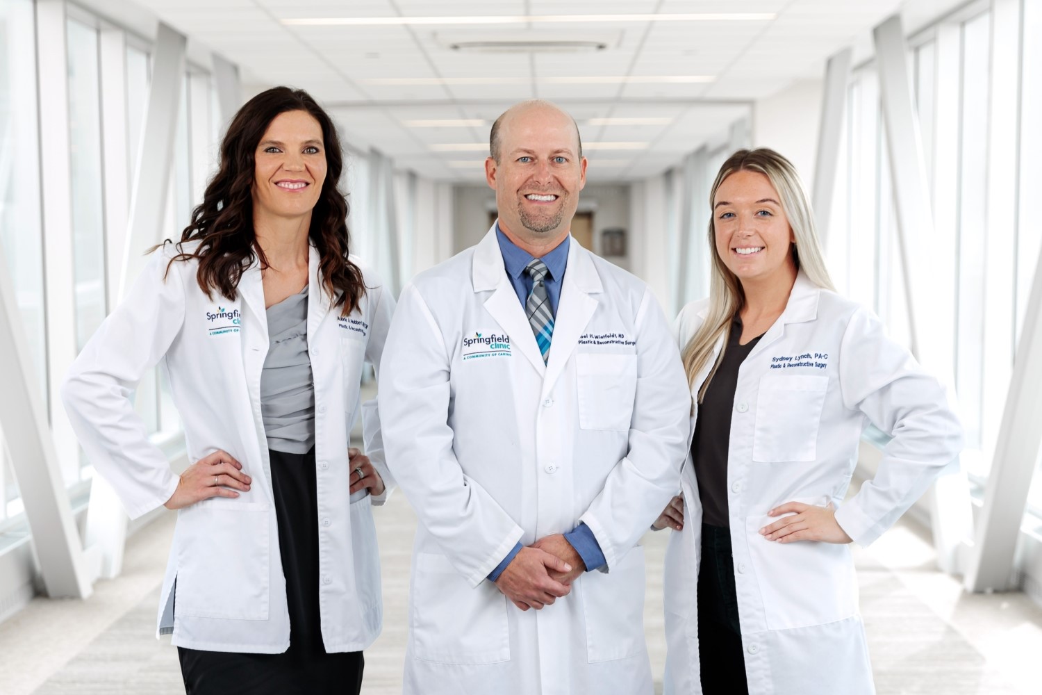 Three plastic surgery providers smiling in medical hallway