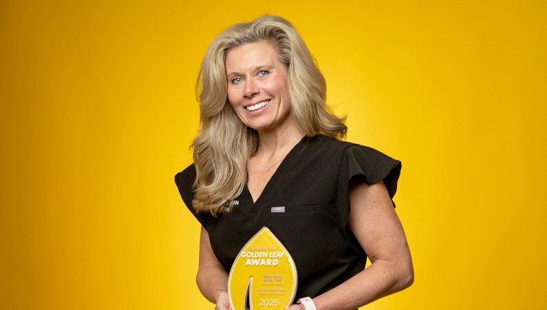 Nurse holding medical award smiling in front of yellow background