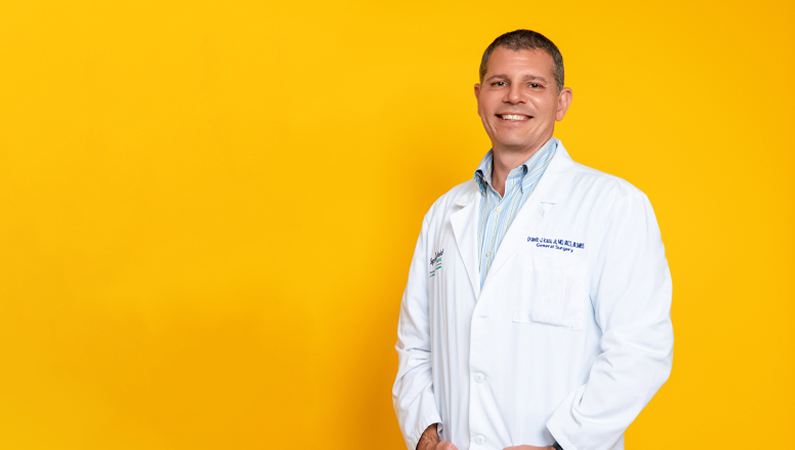 Orlando Icaza smiling in front of a yellow photo backdrop