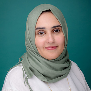 Female endocrinology doctor posing in front of teal photo backdrop.