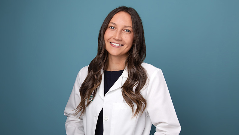 Demi Albracht, APRN, CNP, smiling in front of blue background