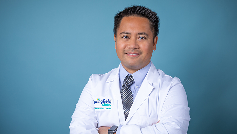 Man smiling in front of a blue backdrop.