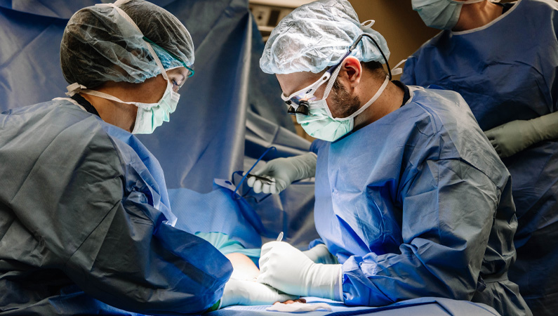 Male doctor in surgical room performing a procedure with female nurse.