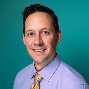 Male nurse practitioner smiling in professional headshot