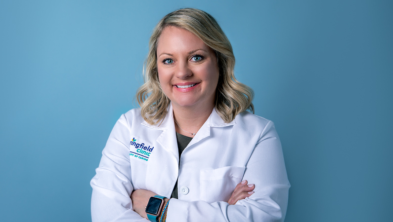 Woman smiling in front of a blue backdrop.