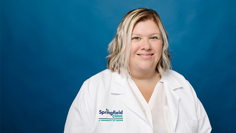 Female family medicine doctor in white coat smiling for professional headshot.