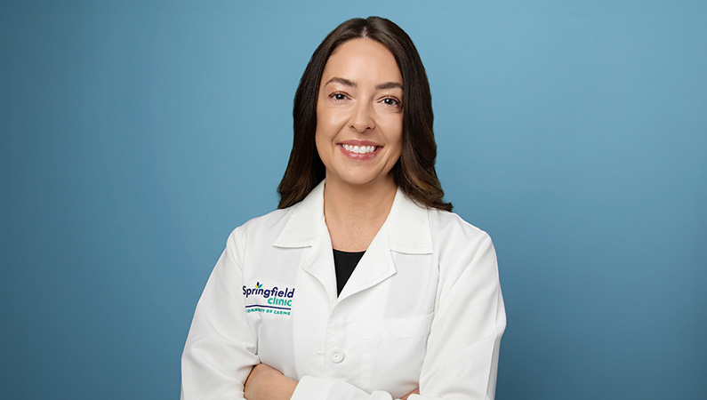 Female wearing white medical coat in front of blue background