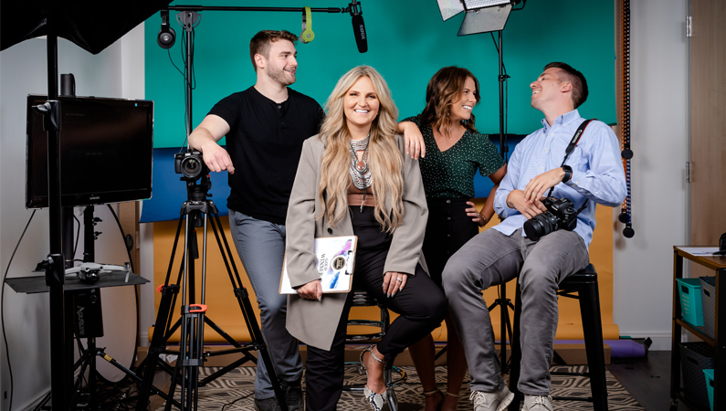 Group of 4 employees in a photo studio setting smiling.