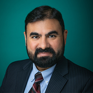Male critical care doctor smiling in professional headshot.