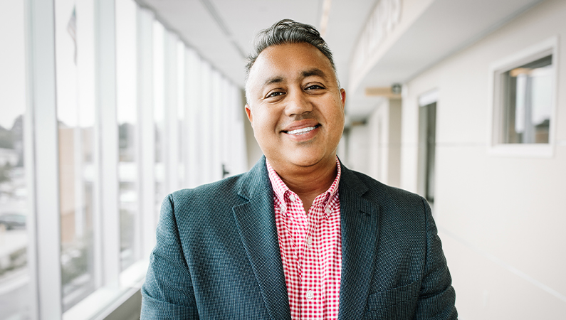 Male wearing suit smiling in well-lit walkway