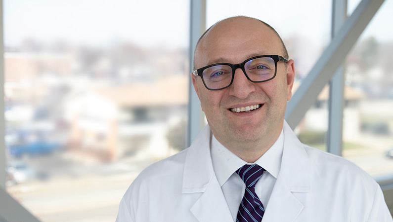 Man smiling in front of a window.