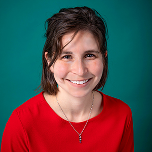 Female nurse practitioner professional headshot in front of a teal blue backdrop.
