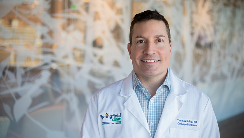 Man smiling in front of a clear wall with tree decals.
