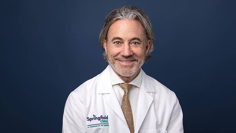 Darryl L. Engeljohn, MD, smiling in front of blue photo backdrop