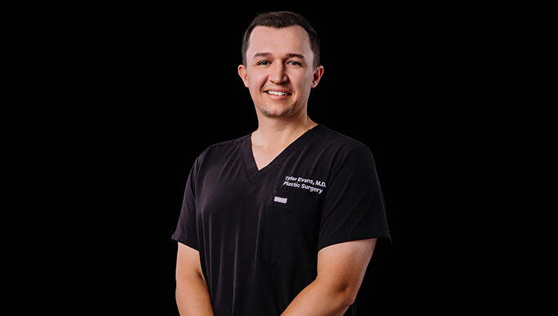 Male physician smiling in front of photo backdrop